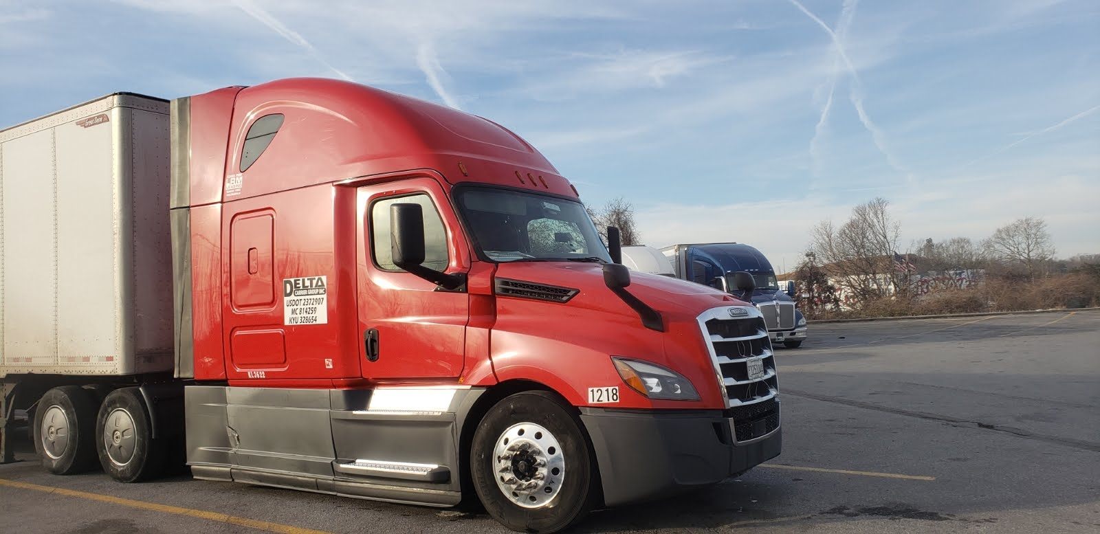 Delta Carrier Group red Freightliner Cascadia, unit 1218, with the company authority numbers on the door
