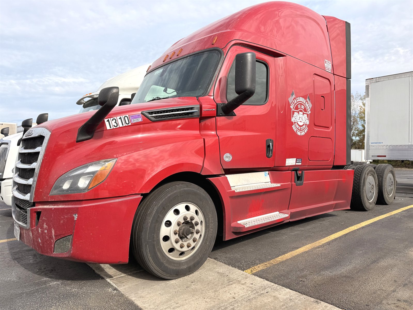 Red Freightliner Cascadia with Delta Carrier Group door badge at the Rockdale yard, unit 1310